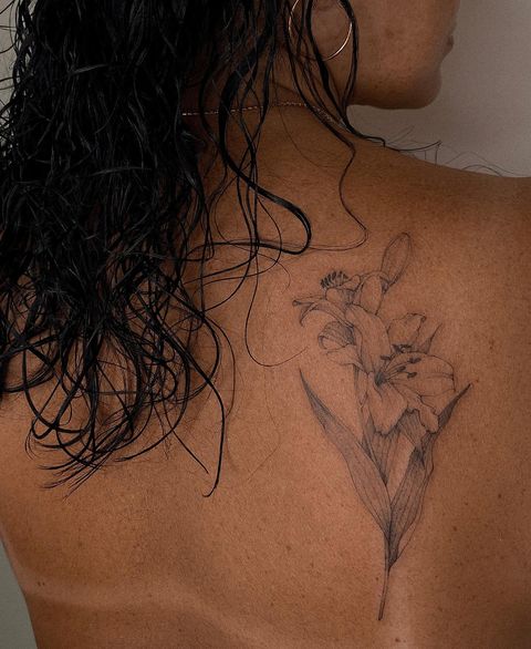 Line art style flower tattoo located on the back.